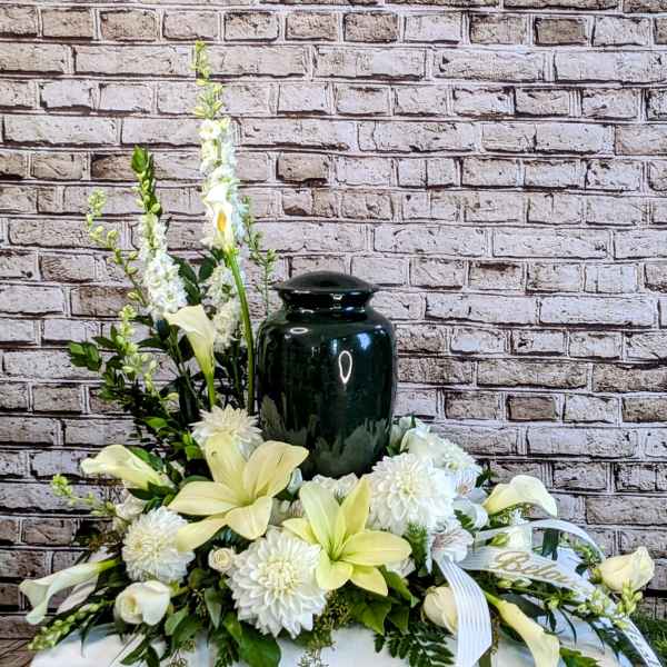 White floral arrangement with a dark urn centerpiece and ribbon accents