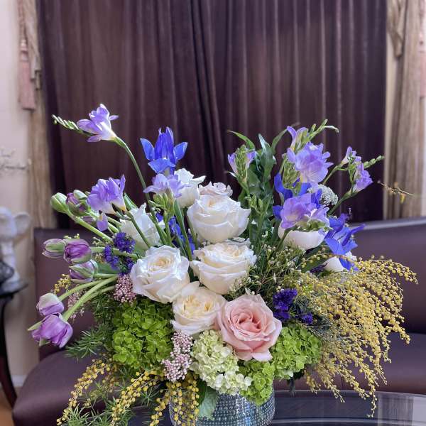 Mixed bouquet of white and pink roses with purple blooms in a glass vase