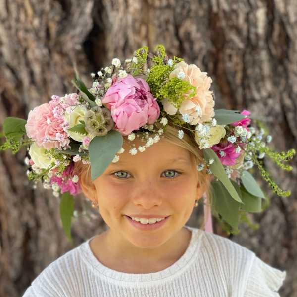 Girl wearing a pastel flower crown with pink and cream blooms