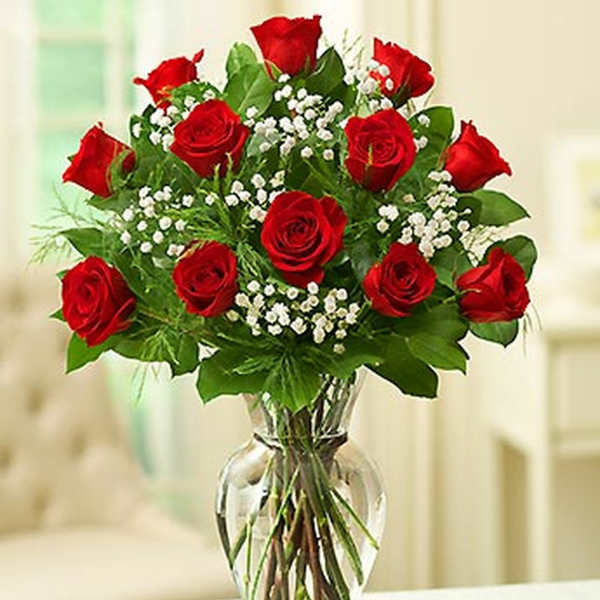 Red roses arranged in a clear glass vase with white filler flowers