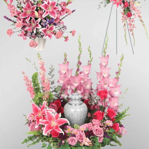 Pink lilies and roses arranged around a silver urn with tall floral sprays