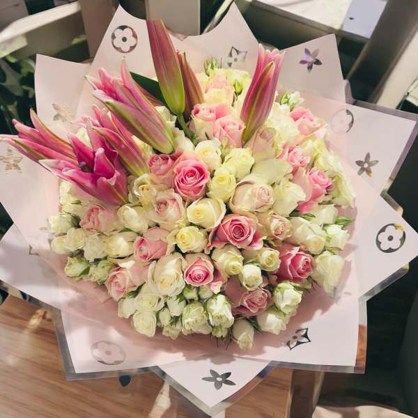 Bouquet of pink and white roses with pink lilies in pastel wrapping