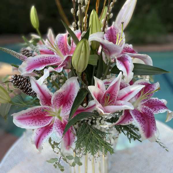 Pink and white lilies arranged in a striped vase