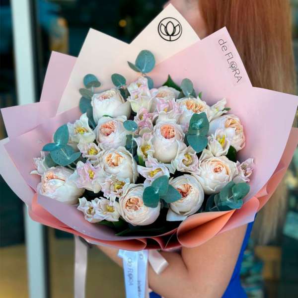 Bouquet of pale pink and white roses wrapped in pink paper