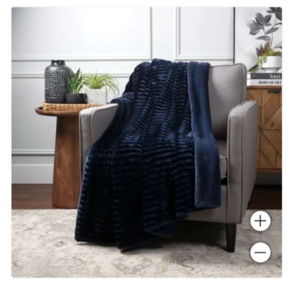 Navy throw blanket draped over a gray armchair with small potted plants nearby
