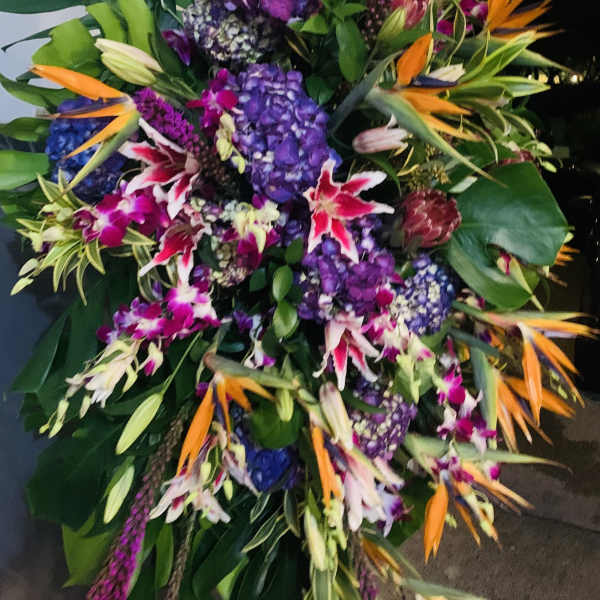 Large tropical floral spray with purple hydrangeas and orange bird-of-paradise blooms