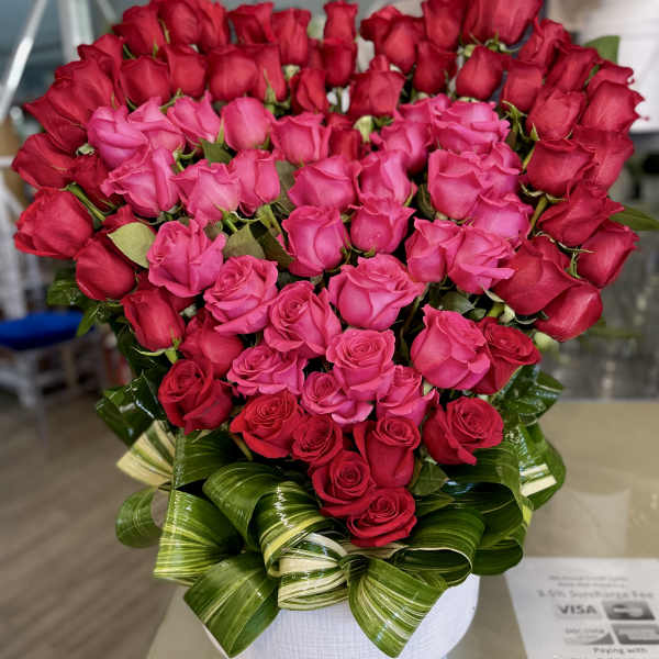 Heart-shaped bouquet of pink and red roses in a white vase