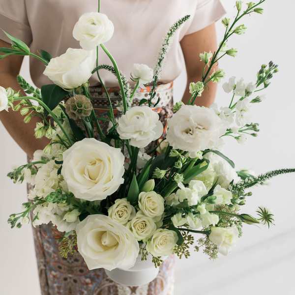 Woman holding a white bouquet of roses and mixed blooms