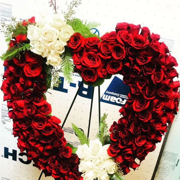 Heart-shaped wreath of red and white roses on a stand