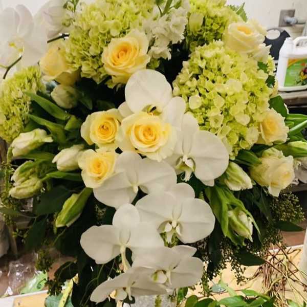 White orchids and pale yellow roses in a silver vase