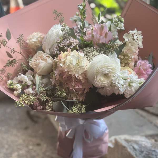 Bouquet of white and blush flowers wrapped in pink paper