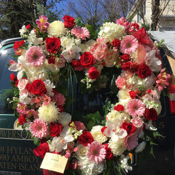 Heart-shaped floral wreath with red, pink, and white flowers on a vehicle