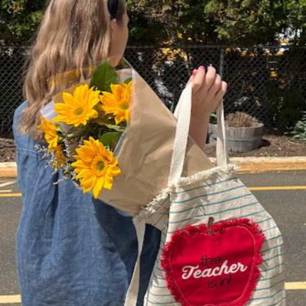 Person carrying a bouquet of yellow flowers and a striped tote bag