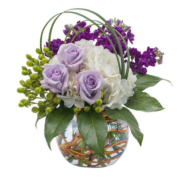 Lavender roses and white hydrangeas in a glass vase with purple flowers