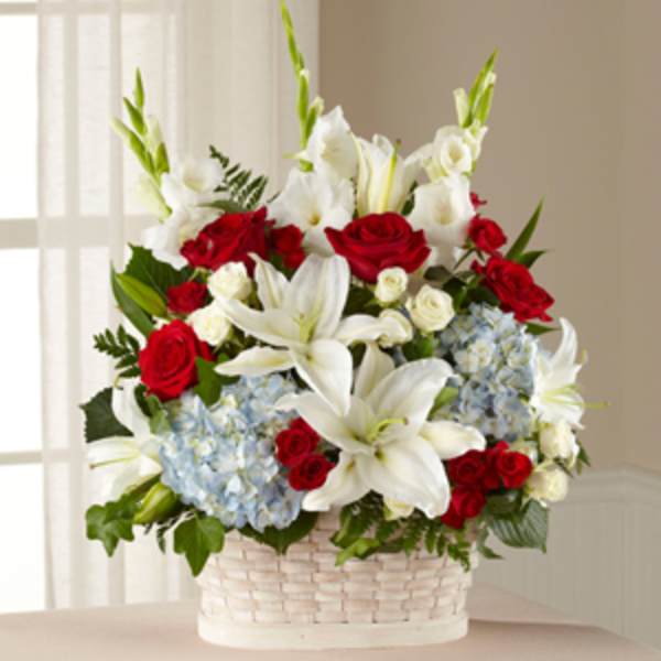 Basket arrangement of red roses, white lilies, and blue hydrangeas