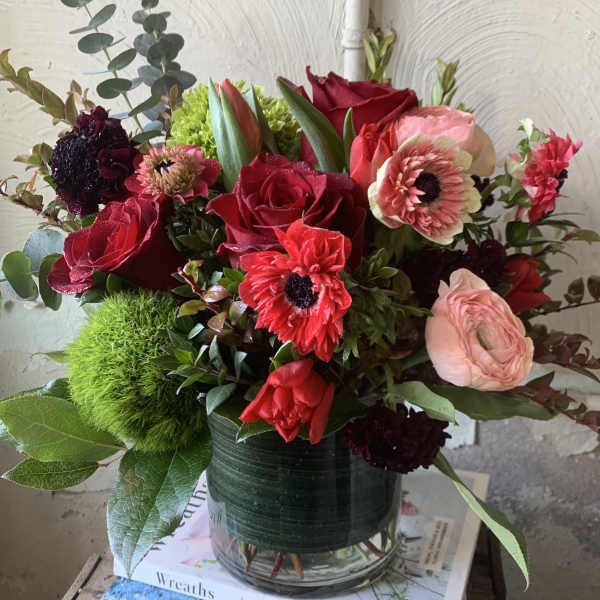 Red roses and pink blooms arranged in a glass vase