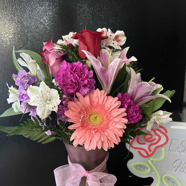 Mixed bouquet with pink gerbera, roses, lilies, and purple flowers in a vase