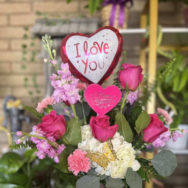 Pink roses and white hydrangeas in a vase with heart balloons