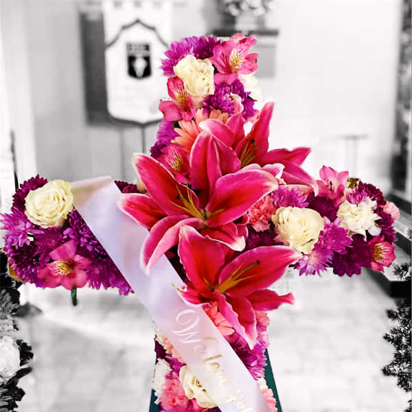 Pink and white floral standing arrangement on an easel with a ribbon sash