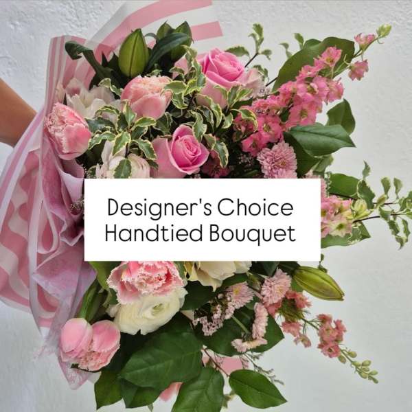 Hand-tied bouquet of pink and white flowers wrapped in pink paper