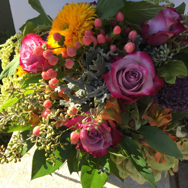 Bouquet of purple and pink roses with yellow blooms and berry accents