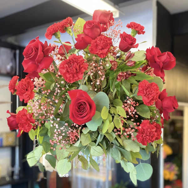 Red roses and carnations in a clear glass vase