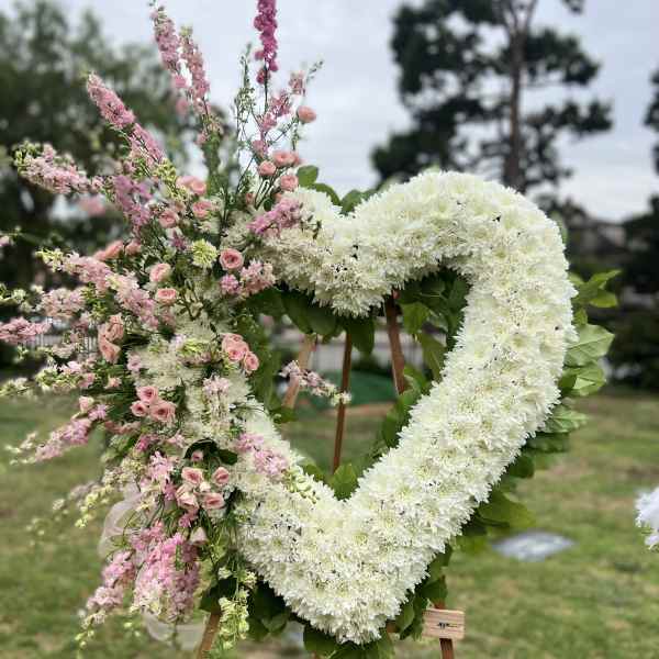 Heart-shaped floral wreath with white and pink flowers on an easel