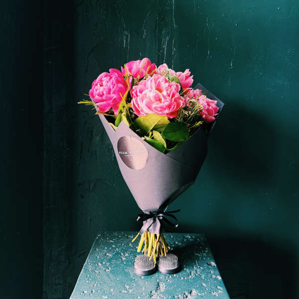 Pink peony bouquet wrapped in dark paper with a black ribbon