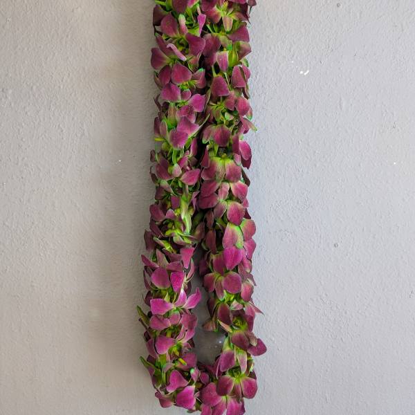 A hanging garland of purple flowers against a plain wall