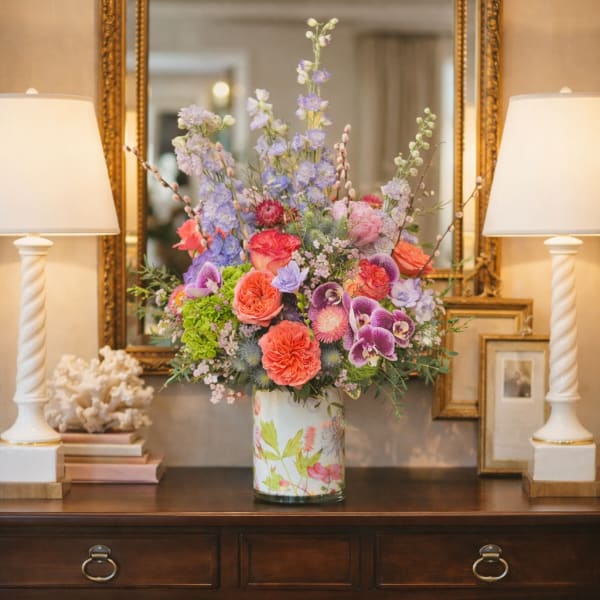Colorful mixed flower arrangement in a floral tin vase on a table