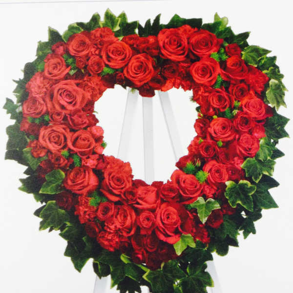 Heart-shaped wreath of red roses on a white easel