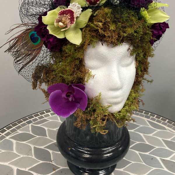 Orchid arrangement with peacock feathers in a black vase