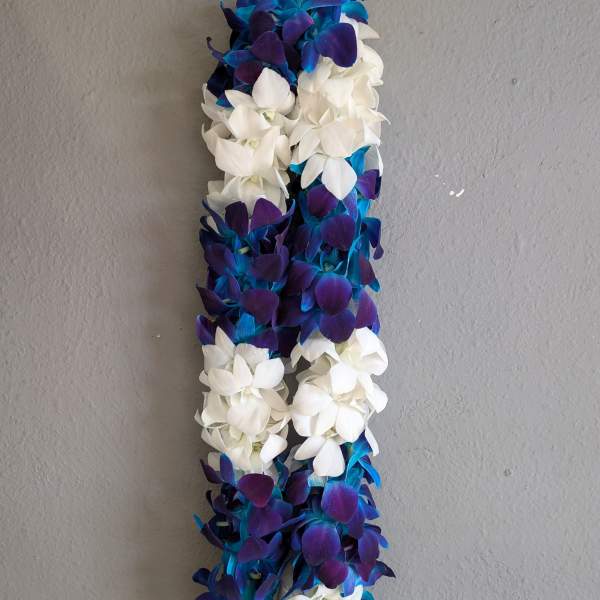 A long floral lei made of white and blue-purple blossoms.