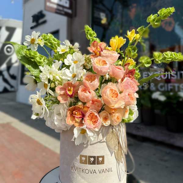 Peach roses and white daisies in a tall hatbox arrangement