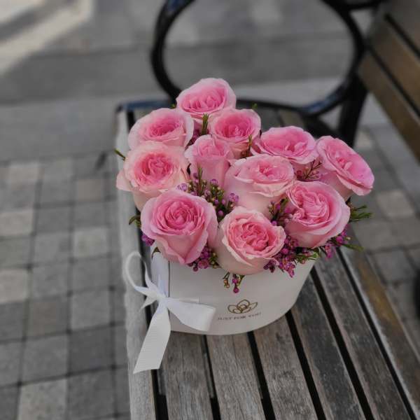 Pink roses arranged in a white round box with a ribbon