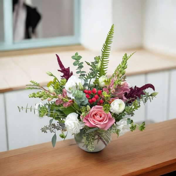 Mixed bouquet in a round glass vase with pink and white flowers