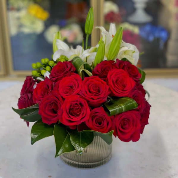 Red roses and white lilies arranged in a clear glass vase