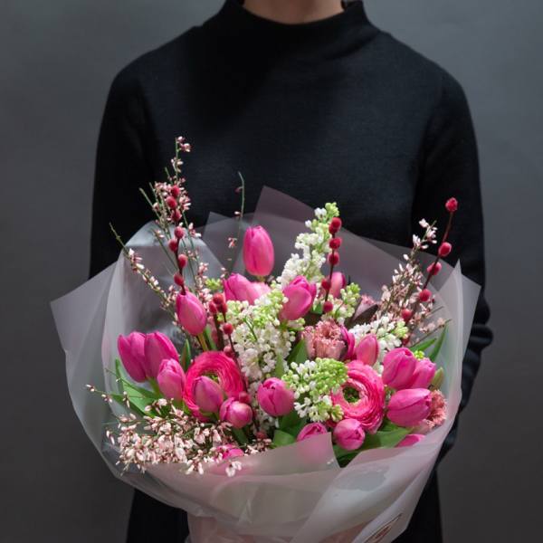 Person holding a bouquet of pink tulips and ranunculus