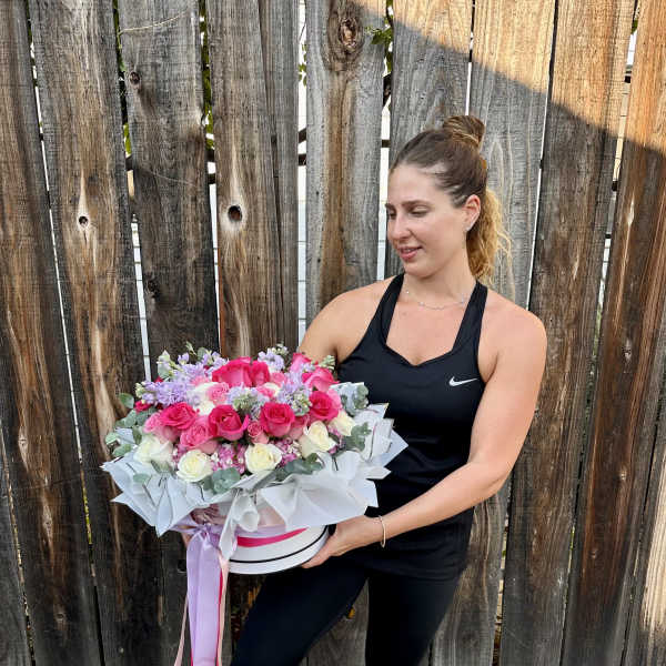 Woman holding a large pink and white rose bouquet in a hat box