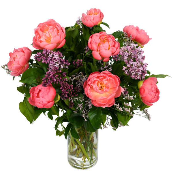 Pink peonies and purple lilac in a clear glass vase