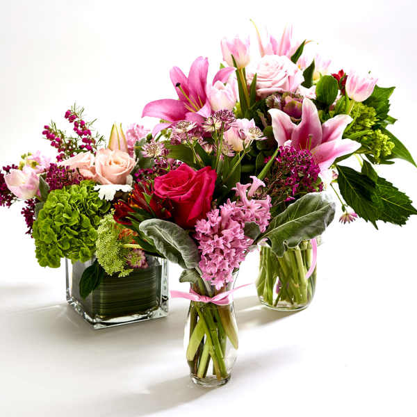 Three colorful flower arrangements in glass vases on a white background