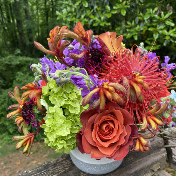 Colorful bouquet with roses, hydrangea, and tropical blooms in a white vase