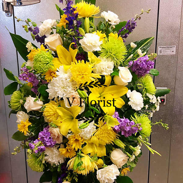 Standing floral spray with yellow, white, and purple flowers