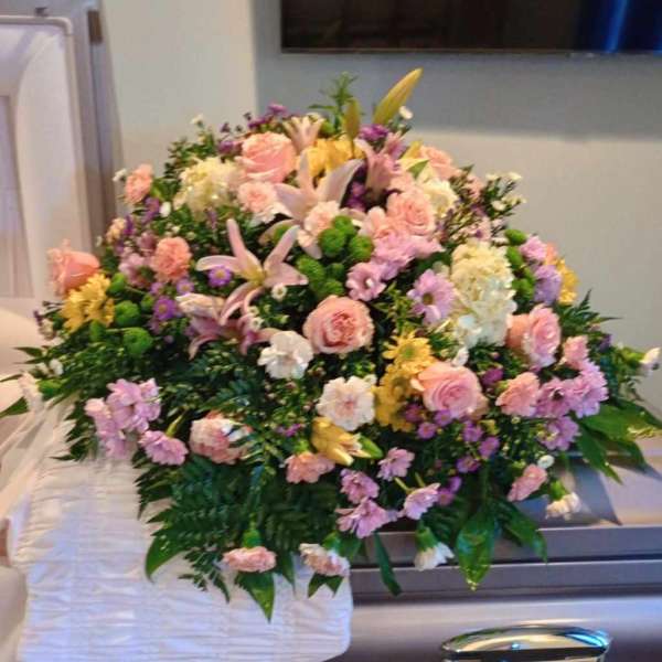 Pastel floral spray on a silver casket