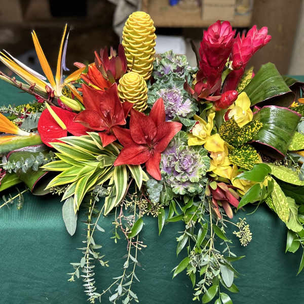 Large tropical floral arrangement with red, yellow, and pink blooms