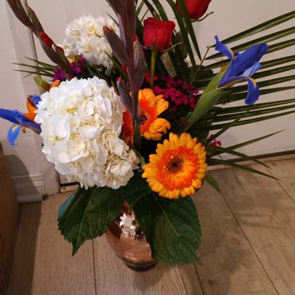 Mixed bouquet with red roses, white hydrangeas, and orange gerbera daisies in a vase