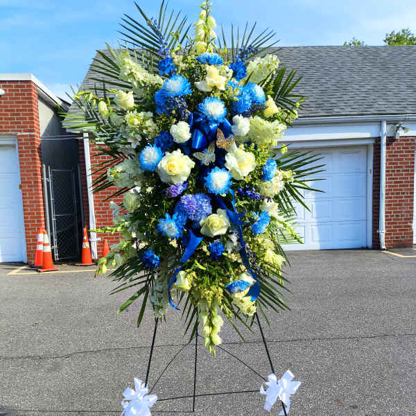 Large standing floral spray with blue and white flowers on an easel