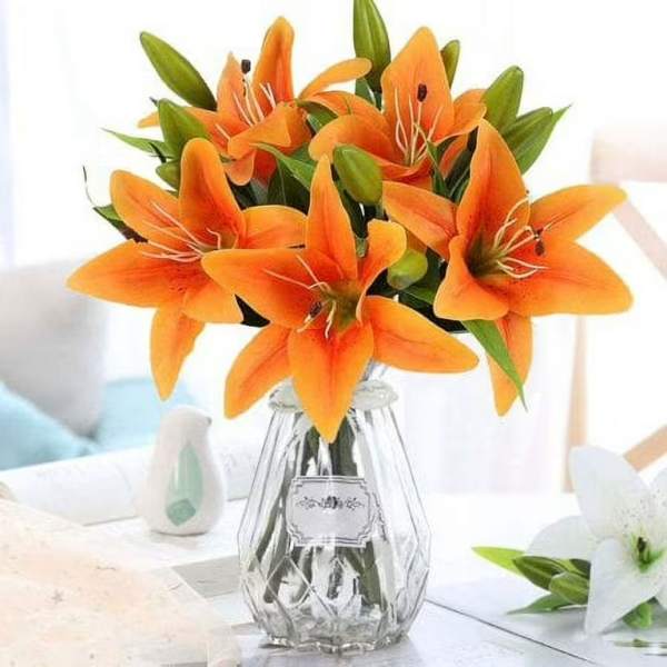 Orange lilies arranged in a clear glass vase