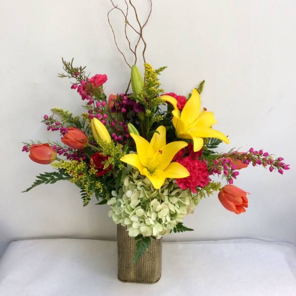 Colorful floral arrangement with yellow lilies and orange tulips in a tall vase