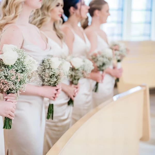 Bridesmaids holding small white rose bouquets